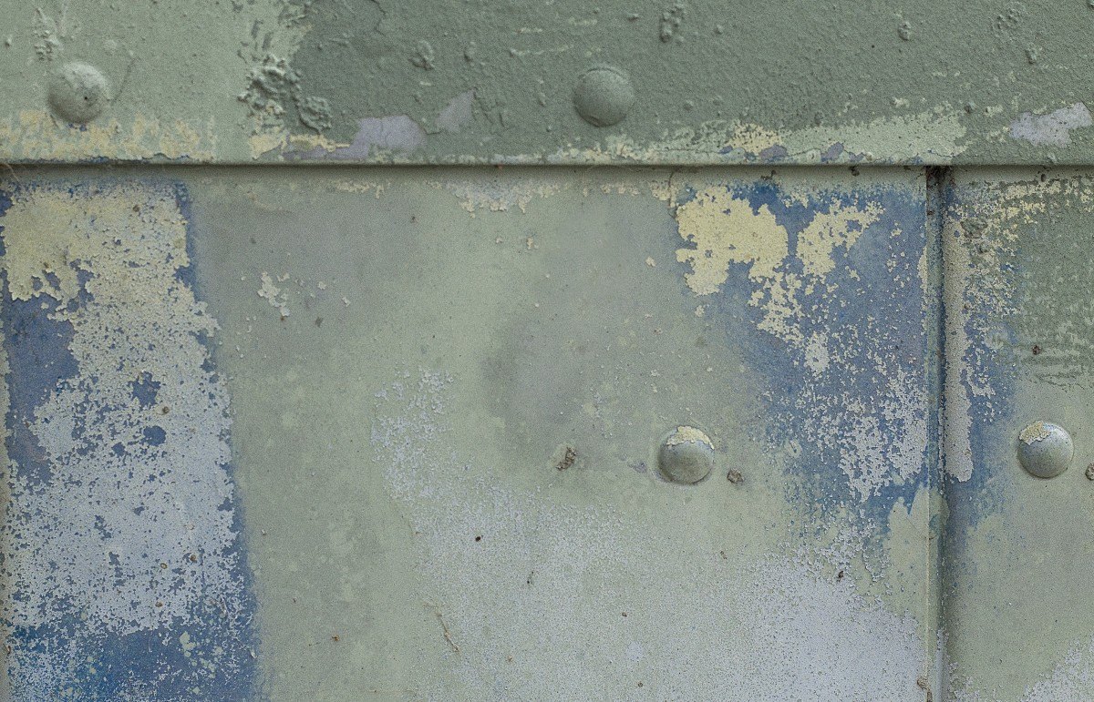 Superficie metálica con pintura deteriorada y remaches